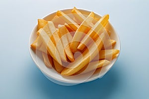 Salty French fries in a white bowl on a light background. Fast food concept.