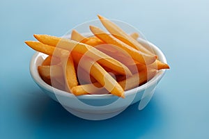 Salty French fries in a white bowl on a light background. Fast food concept.