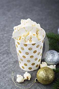 Salty fresh crusty homemade popcorn in silver paper cup in the fashion light background of white brick wall in a New