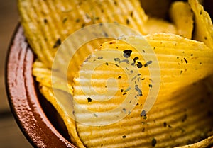 Salty grooved chips in ceramic bowl on the rustic background. Selective focus. Shallow depth of field