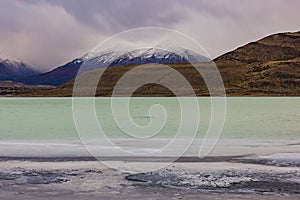 The salty Laguna Amarga in front of the cloudy mountains in Torres del Paine National Park, Chile