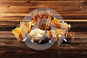 Salty snacks. Pretzels, chips, crackers in glass bowls on table