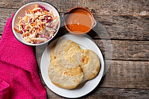 Salvadoran pupusas with coleslaw and tomato sauce on wooden background