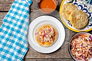 Salvadoran pupusas with coleslaw and tomato sauce on wooden background