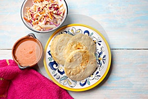 Salvadoran pupusas with coleslaw and tomato sauce on wooden background