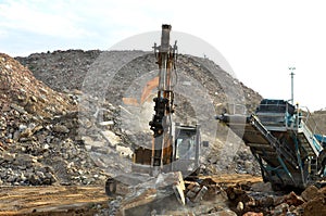 Salvaging and recycling building and construction materials. Excavator with hydraulic hammer work at landfill with concrete