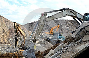 Salvaging and recycling building and construction materials. Excavators work at landfill with concrete demolition waste. Recycling