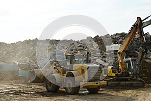 Salvaging and recycling building and construction materials. Industrial waste treatment plant. Excavator and a front-end loader