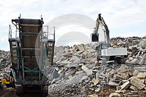 Salvaging and recycling building and construction materials. Industrial waste treatment plant. Excavator work at landfill with