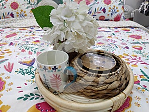 Salver with cup, flower and candle on bed photo