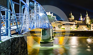 Salzburg night lights from the Salach river with the old iron bridge.