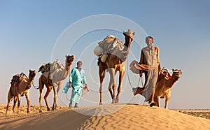 Camel man leads his camels across the Thar desert