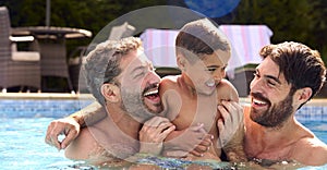 Same Sex Family With Two Dads And Son On Holiday In Swimming Pool Together