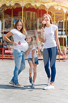 Samesex lesbian family with child on a walk in the amusement park. Lesbians mothers with adopted child, happy family