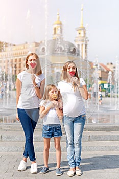 Samesex lesbian family with child on a walk in the park near the fountains. Lesbians mothers with adopted child, happy