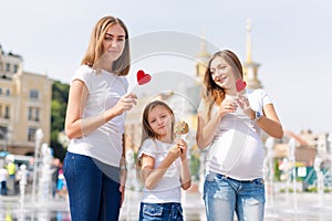 Samesex lesbian family with child on a walk in the park near the fountains. Lesbians mothers with adopted child, happy