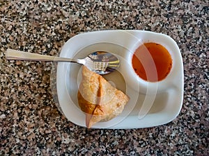 Samosa with chutney or sauce served in a white plate. Top view