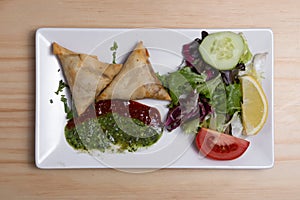 Samosa with lettuce on a wooden table