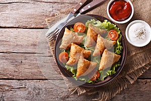 Samosa on a plate with sauce, horizontal top view