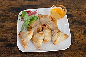 samosa in a white plate with sweet and sour sauce