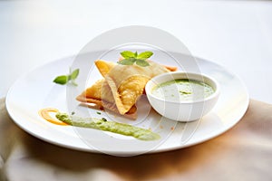 samosas with mint chutney on a white dish