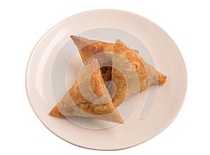 Samosas a spicy blend of vegetables or meat wrapped in a deep fried triangular pastry parcel in a white plate.