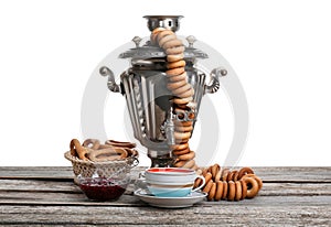 Samovar with hot tea, jam and delicious ring shaped Sushki dry bagels on table against white background