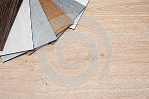 Sample catalog of luxury vinyl floor tiles with a new interior design for a house or floor on a light wooden background.