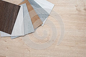 Sample catalog of luxury vinyl floor tiles with a new interior design for a house or floor on a light wooden background.