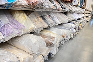 Sample fabric rolls in warehouse. Rolls of fabric are packed in plastic bags. Fabric warehouse with many textile rolls