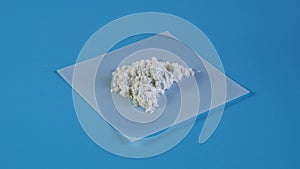 Sample of Guar gum powder or guaran rotating clockwise on blue background.