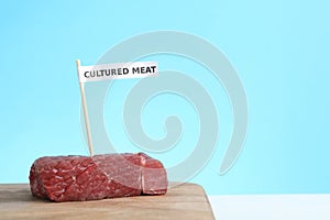 Sample of lab grown beef labeled Cultured Meat on wooden table. Space for text