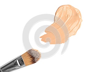 Sample of liquid foundation and makeup brush on white background