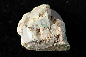 sample of raw amazonite rock on black granite