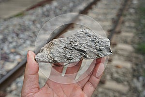 Sample raw specimen of granite igneous rock stone on Geologist's hand.