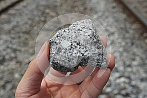 Sample raw specimen of granite igneous rock stone on Geologist's hand.