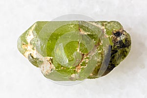 sample of rough peridod crystal on white marble
