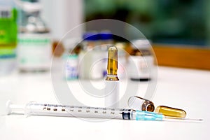 Sample vials and plastic syringe with 3 ml. ampule is opened on white table with ampule blurry background