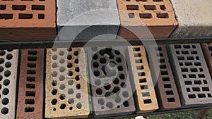 Samples of bricks differ in shape and color displayed in a row at the exhibition stand. Different types of construction