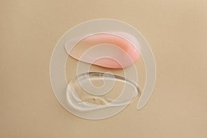 Samples of cosmetic gels on beige background, top view