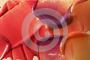 Samples of different lipglosses on beige background, closeup