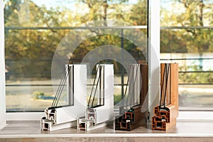 Samples of modern window profiles on sill indoors.