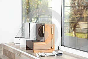 Samples of modern window profiles on sill indoors, space for text.