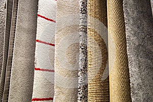 Samples of synthetic carpets of various patterns of white yellow gray color suspended on the crossbar. Textiles, Backgrounds, desi