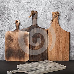 Samples of various rustic wooden cutting boards on a kitchen countertop against a concrete wall. Manufacture of