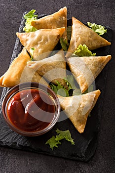 Samsa or samosas with meat and vegetables on black background. Traditional Indian food.