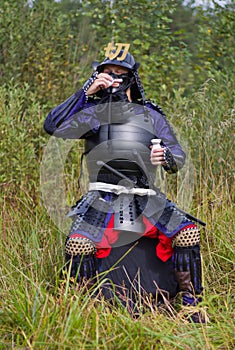 Samurai in armor drinking sake from cup