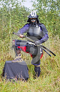 Samurai in armor pulling out katana sword