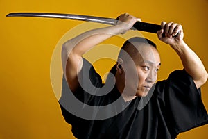 Samurai in black kimano raised his sword up, on a yellow background