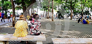 Samut Songkhram, Thailand - June 23, 2018: Old Asian women relaxing, talking and sitting beside on marble bench in park with green